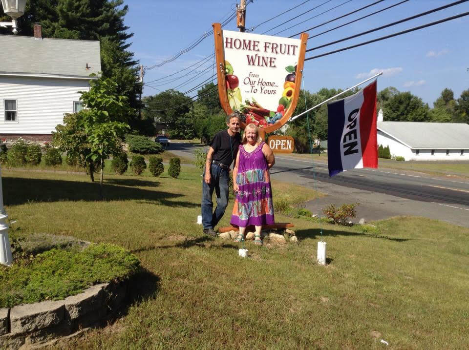 photo of the owners posing in front of their business signage on the side of the road